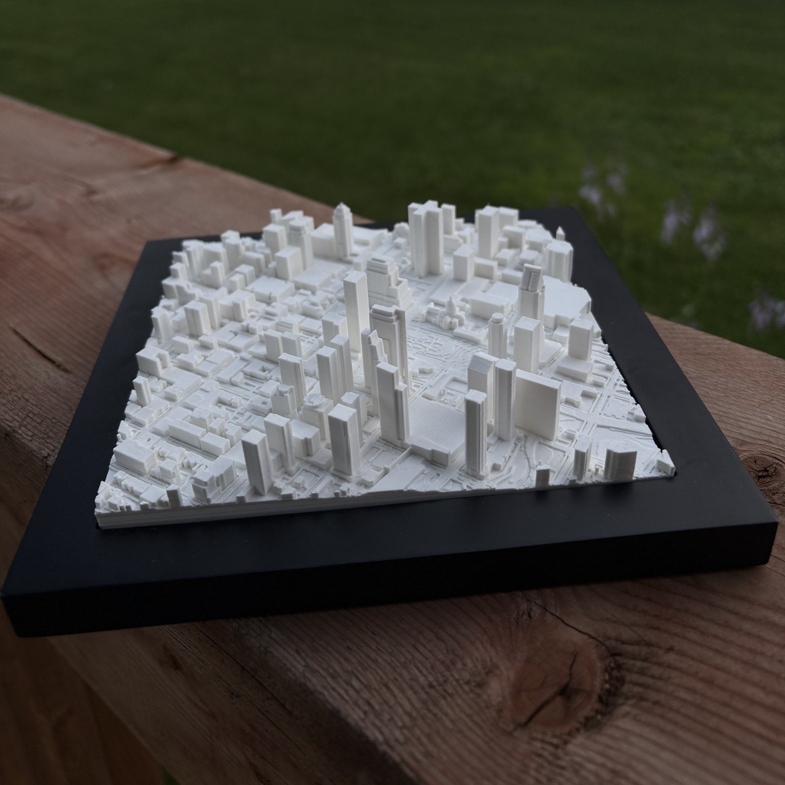A Mini City Prints framed cityscape resting on a wooden deck rail